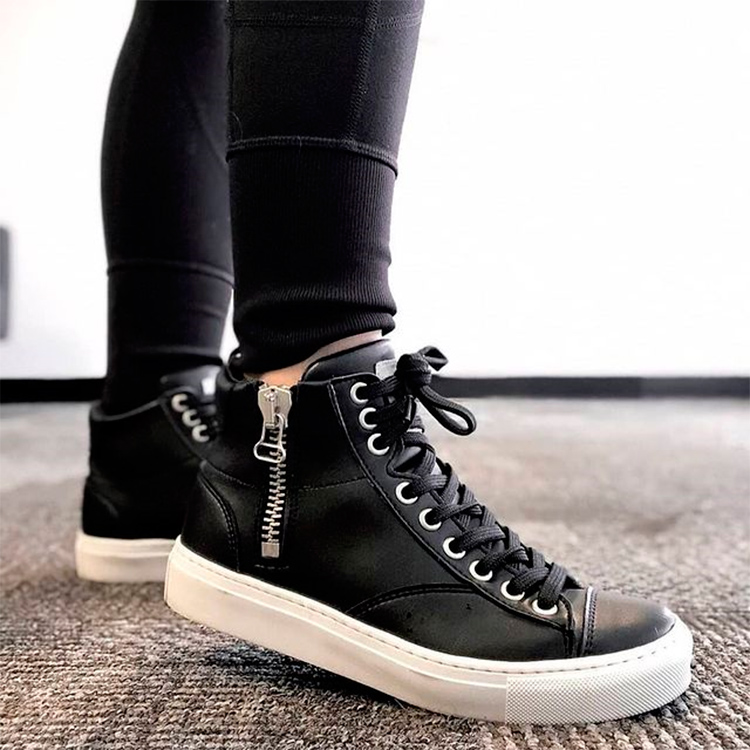 A girl wearing black vegan trainers from Nae with a zip