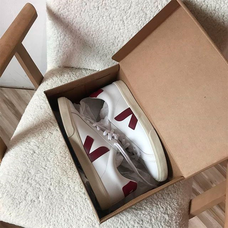 A pair of the most iconic white Veja vegan trainer in a box